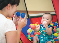 写真：ボールで遊ぶ赤ちゃんと大人