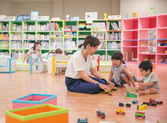 写真：おもちゃで遊ぶ子どもと大人